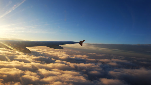 wing of a Airplane at sunset with clouds. Travel, adventure, transport concept. View from the wing window at sunset.