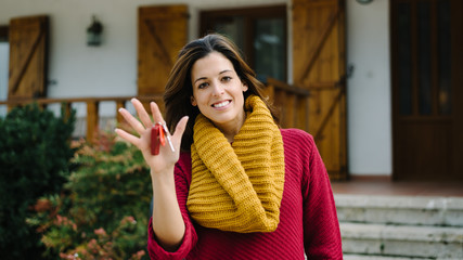 Owner showing house keys. Real estate ownership concept. Woman outside her home.