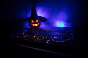 Halloween pumpkin on a dj table with headphones on dark background with copy space. Happy Halloween...
