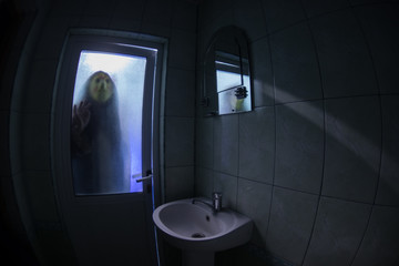 Horror silhouette of woman in window. Scary halloween concept Blurred silhouette of witch in bathroom. Selective focus