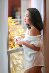 portrait of young and sexy woman wake up and see view from bedroom window