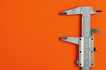 Vernier caliper of gray color on orange table with copy space for your text
