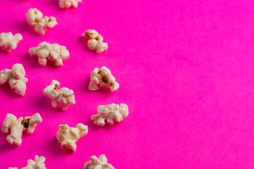 Scattered cooked popcorn on pink background with copy space. Сoncept of leisure