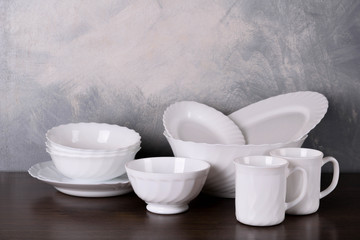  White dishware stacked on a wooden table against grey background on wooden table