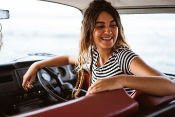 young woman driver smiling and look back on road trip