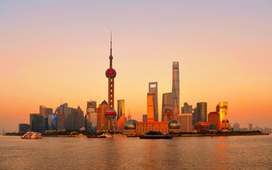 Cityscape and panorama of modern architecture,  warm colors and sunset on river of shanghai pudong skyline and skyscrapers, China