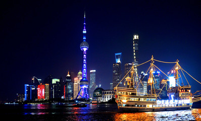 colorful lights and futuristic skyline and boats on river of shanghai pudong skyscrapers, China