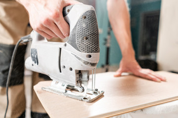 Male worker cuts the laminate Board with an electrofret saw. installing new wooden laminate flooring. concept of repair in house.