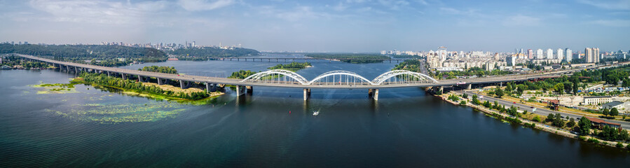 Aerial panorama view of automobile and railroad Darnitsky bridge across Dnieper river from above, Kiev city skyline