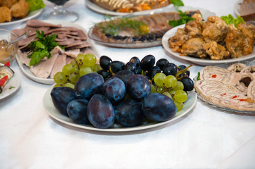 Plum fruits, grapes, meat, fish and roll on a festive New Year's table