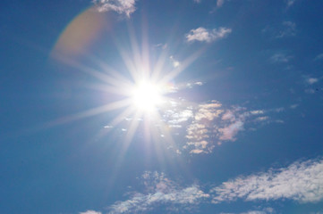 Blue sky with clouds and sun. Strong sun, divine sky