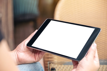 Mockup image of a woman sitting and holding black tablet pc with blank white desktop screen