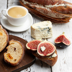 Sandwich with figs, cheese and a Cup of coffee on a wooden background.