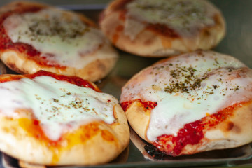 Mini pizza with ham, mozzarella, tomato sauce from the oven in bakery shop of Catania, Sicily, Italy