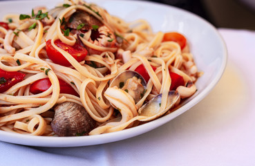 Seafood pasta spaghetti linguine wish mussels, clams, cherry tomatoes, fresh parmesan on the white plate in restaurant in Catania, Sicily, Italy