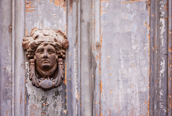 Exterior vintage door knocker metal circle on a door of an ancient building in Catania, Sicily, Italy