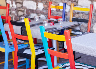 Fototapeta na wymiar Tables with multi-colored chairs on the terrace in a cafe in Taormina, Sicily, Italy