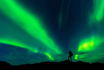Fototapeta na wymiar Aurora borealis with silhouette standing photographer on the mountain.Freedom traveller journey concept