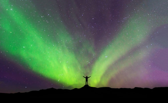 Aurora borealis with silhouette standing man on the mountain.Freedom traveller journey concept