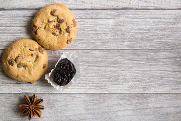 Tasty cookies with chocolate crumbles on grey wooden table background, date and anise star decoration,  top view, close up. Copy space.