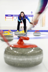 Rozgrywki curlingowe.  Zawodnik szczotkuje lód kierując kamień do domu - obrazy, fototapety, plakaty