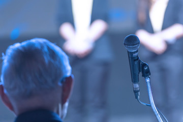 Speaker giving a talk on corporate Business Conference hall or seminar room background.