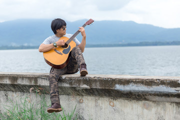 Guy with guitar standing on the dam,  cargo pants