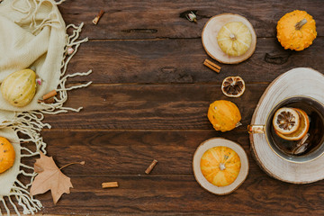 Flat lay, top view of vintage autumn composition. Pumpkins, dry leaves and hot tea on wooden background