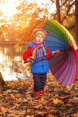 Child in autumn park. Happy adorable boy with fall leaves. The concept of childhood, family and kid laughs outdoors. 
