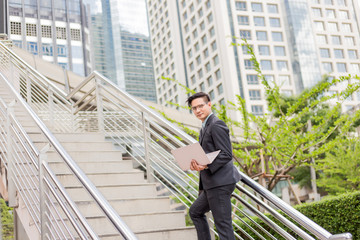 Business man with his laptop going up the stairs  in a rush hour to work . Hurry time.