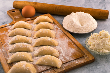 Dough dumplings with cottage cheese filling on the kitchen cutting Board.