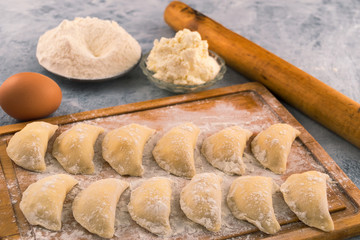 Dumplings on the cutting Board, next to the ingredients-chicken egg, flour, cottage cheese.