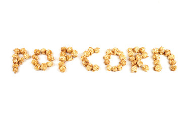 The word POPKORN is laid out from pieces of caramel popcorn on a white background.