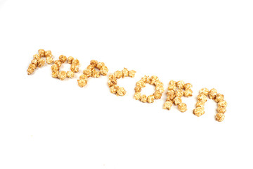 The word POPKORN is laid out from pieces of caramel popcorn on a white background.