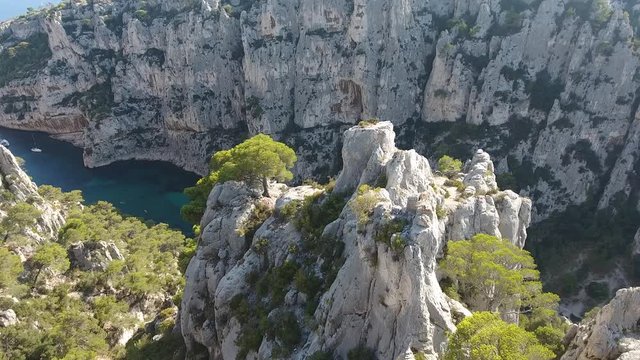 Amazing drone shot flying between a trees and rocks discovering two man watching a beautiful creek. Calanque d'en vau in south of france. Sunny day