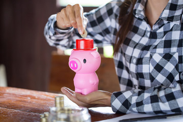 Female hand putting coin into piggy bank closeup. concept saving money for finance