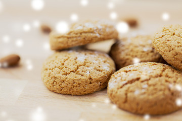 food, baking and winter concept - close up of homemade oatmeal cookies on wooden table over snow