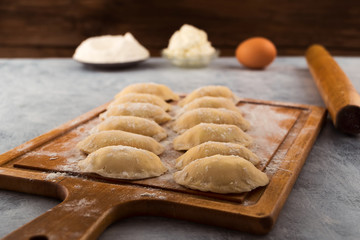 Raw dumplings with cottage cheese filling, laid on the kitchen cutting Board.
