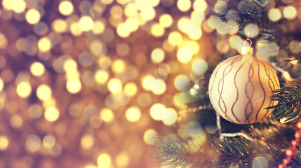 Christmas golden ball hanging on a pine tree. Field to insert text to the left