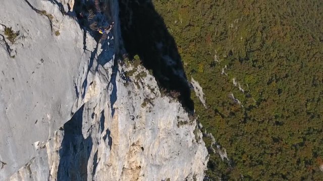 Man base jumping in slow motion from a cliff in choranche vercors massif France. Drone shot.