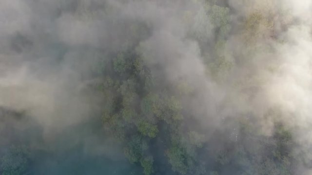 Aerial mystic shot flying over a cloudy forest discovering a cliff in Vercors France. Sunny morning