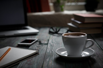 A cup of coffee in the workplace on a wooden table.