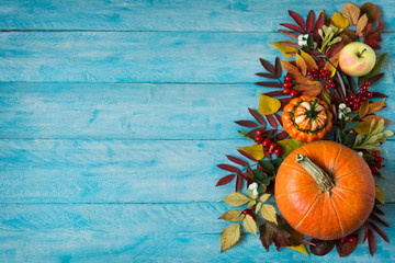 Fall border of apples, berries, pumpkins on blue table, copy space