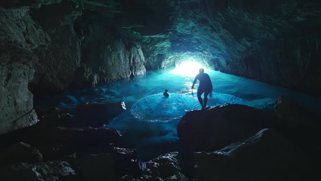Three man jumping in the water inside a blue cave in the calanques. Marseille south of France.