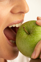 YOUNG WOMAN EATING GREEN APPLE IN CLOSE UP