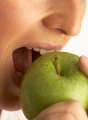 YOUNG WOMAN EATING GREEN APPLE IN CLOSE UP