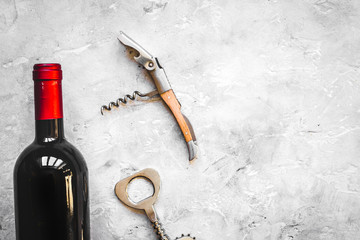 glass wine bottle and corkscrew on concrete background top view