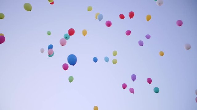Multicolored party ballons flying in the sky sunset time.