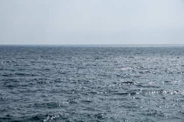 Deep blue surface of a calm sea merging with the empty sky