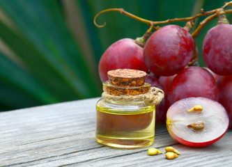 Grape seed oil in a glass jar and fresh grapes on old wooden table in the garden.
Spa,bodycare,Bio,Eco products concept.
Selective focus.